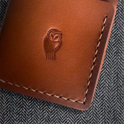 Handmade leather cardholder in windsor tan, stitching detail on cloth background